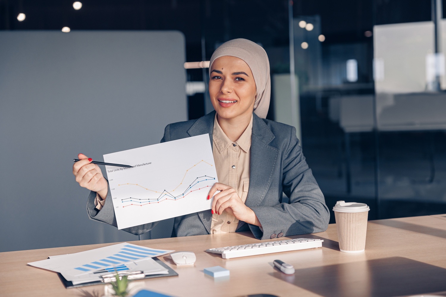 smiling-muslim-businesswoman-in-hijab-shows-a-grap-AMH74W7
